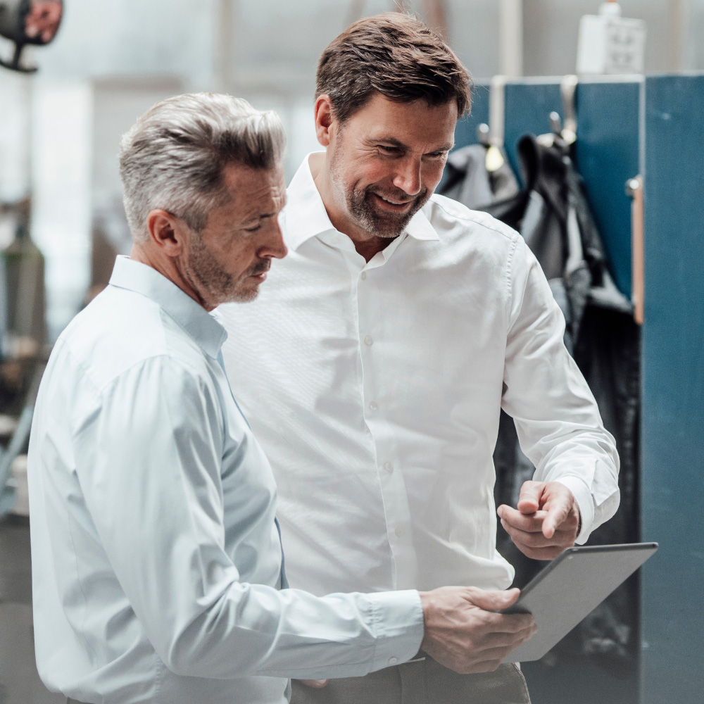 Businessman discussing with male colleague over digital tablet in industry Prozess-Spezialist anfordern